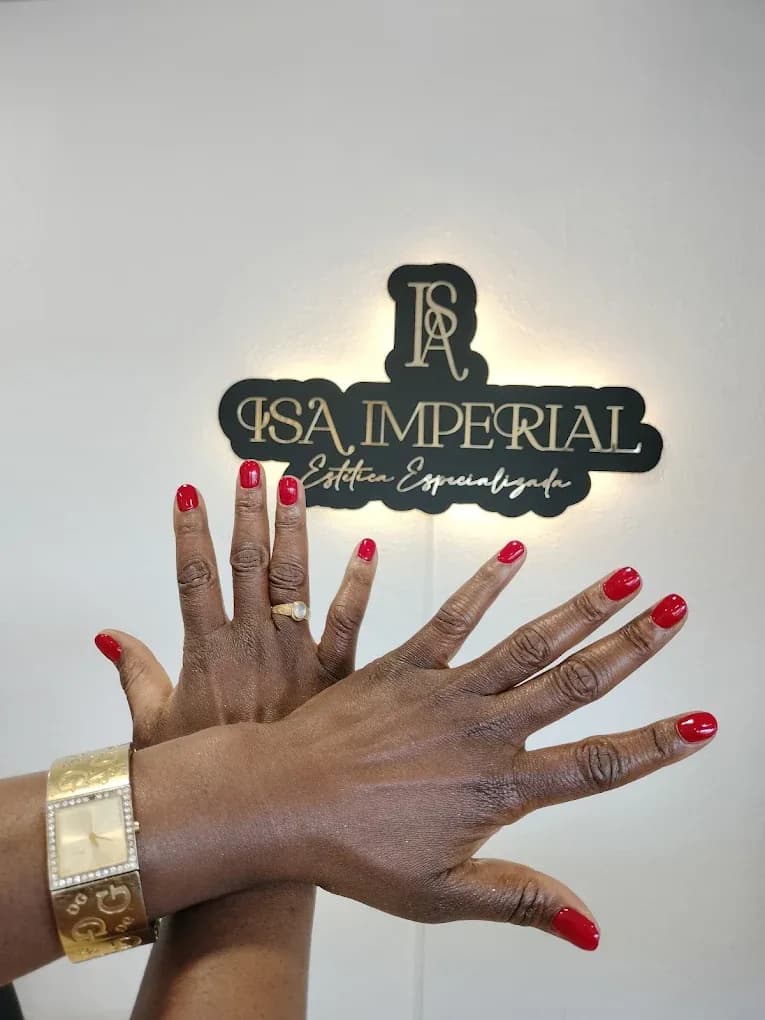 Mãos com unhas vermelhas em frente ao letreiro iluminado Isa Imperial