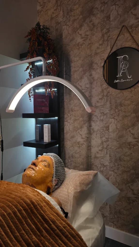 Cliente com máscara facial dourada sob a lâmpada LED