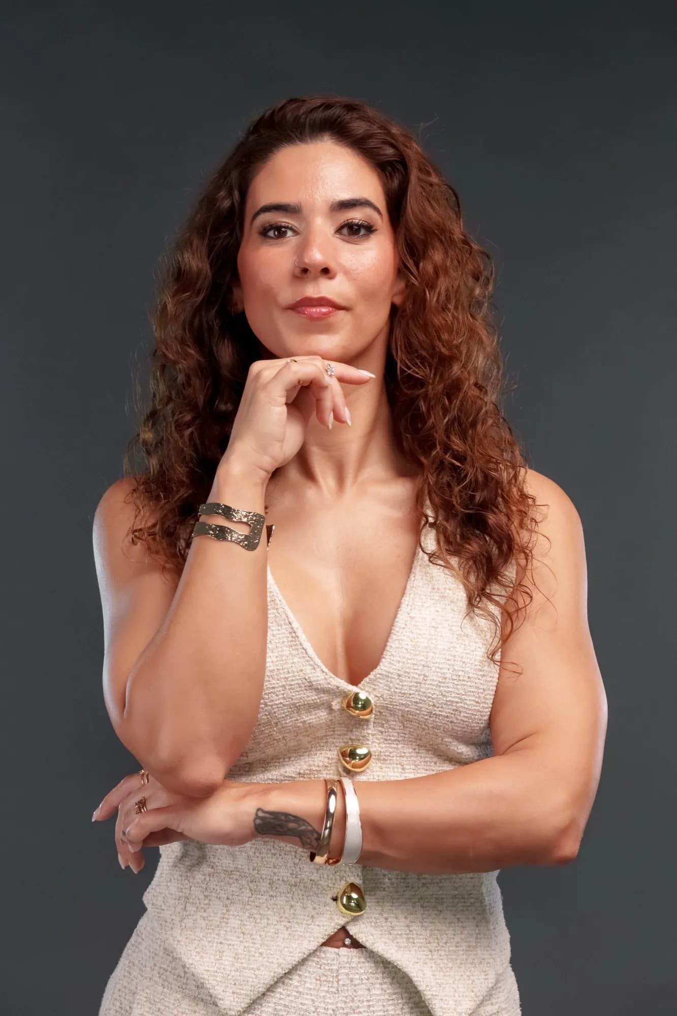 Retrato de Isa em estúdio, de colete creme e pulseiras douradas