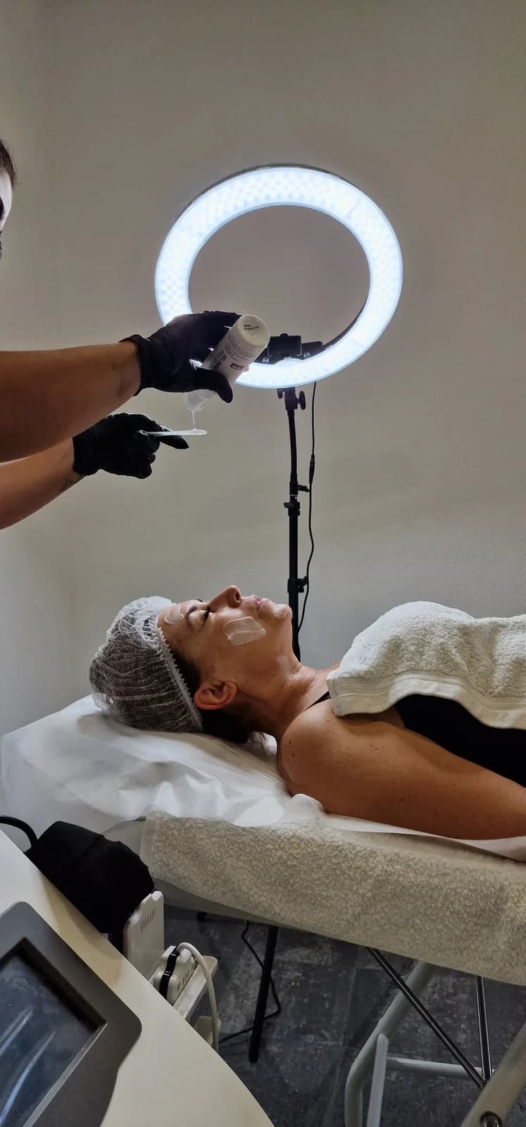Tratamento facial com aparelho, sob a luz de um anel de LED